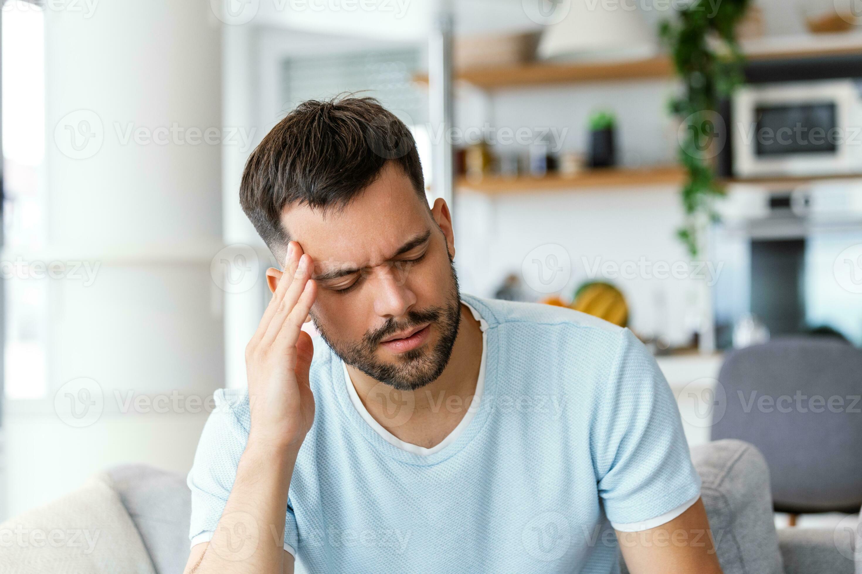 Man at home having a headache. Young man suffering from headache after