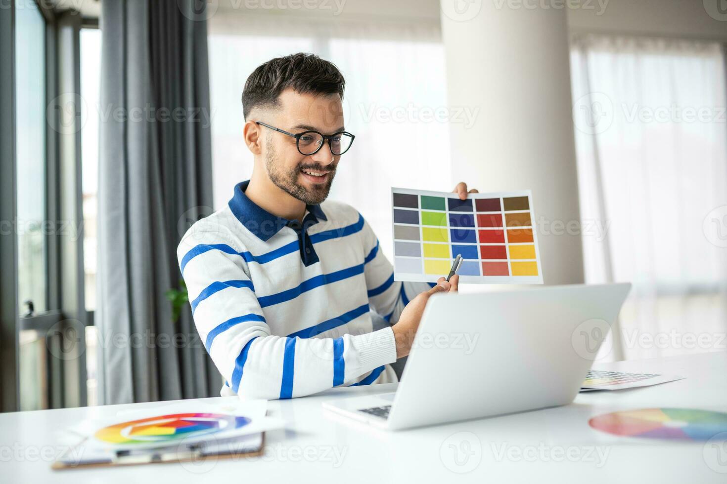 Graphic Design Courses Online. Young Man Holding Colour Swatch And Using Laptop Computer At Home, Study In Internet, Male Freelance Designer Planning Gamma For Future Interior, Free Space photo
