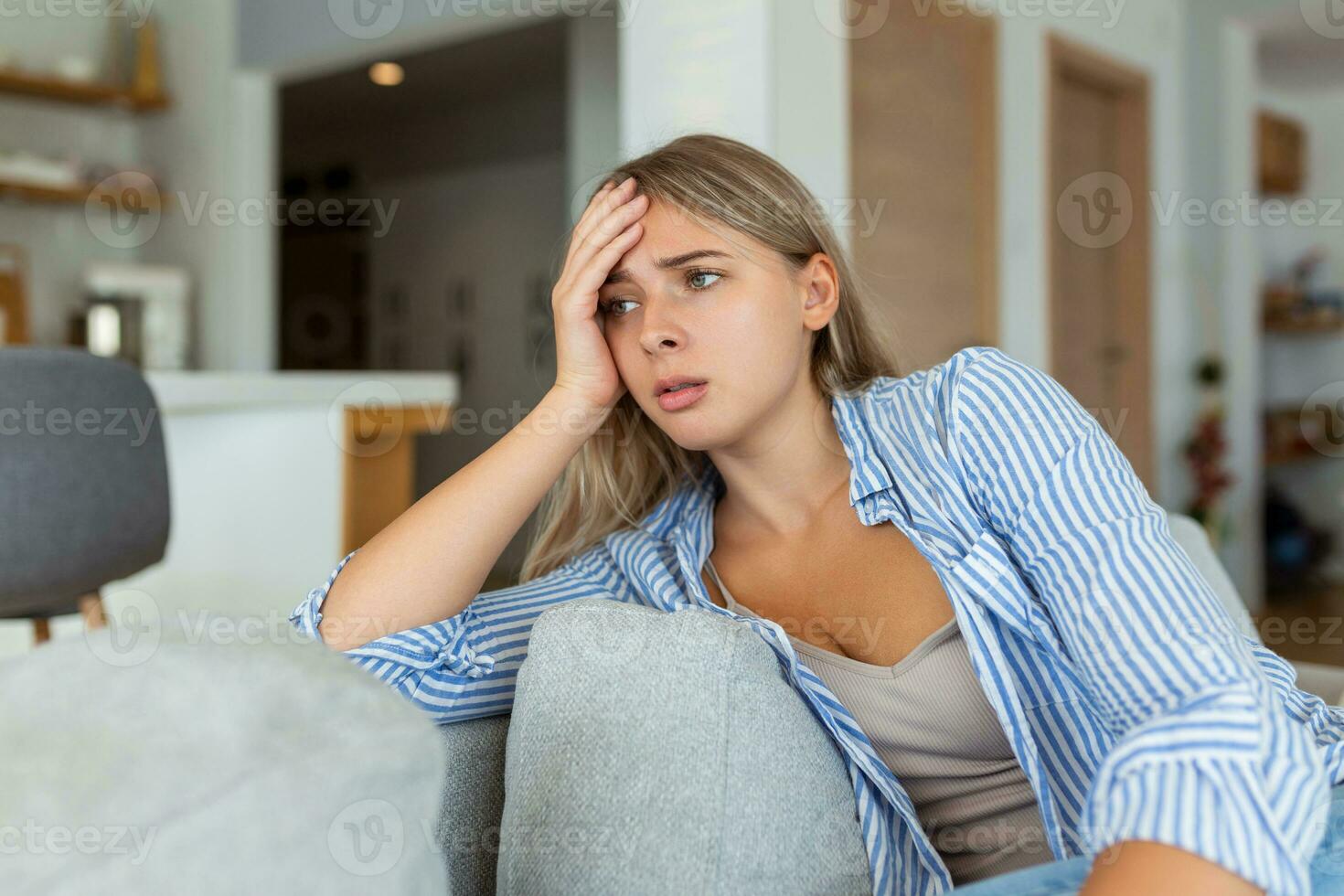 anxious worried woman sitting on couch at home. Frustrated confused female feels unhappy, problems in personal life, quarrel break up with boyfriend and unexpected pregnancy concept photo