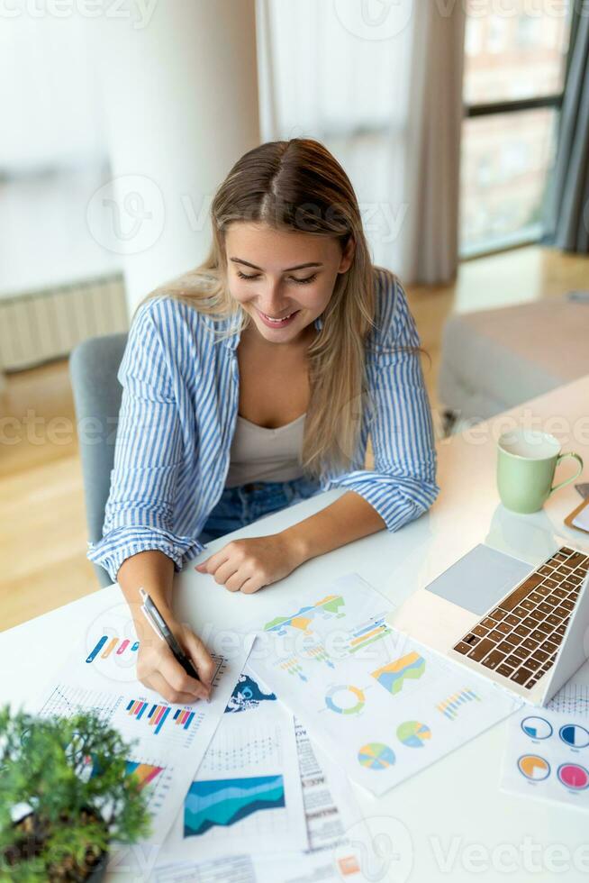 Young woman working laptop. Business woman busy working on laptop computer at office. Businesswoman sitting at bright modern work station and typing on laptop photo