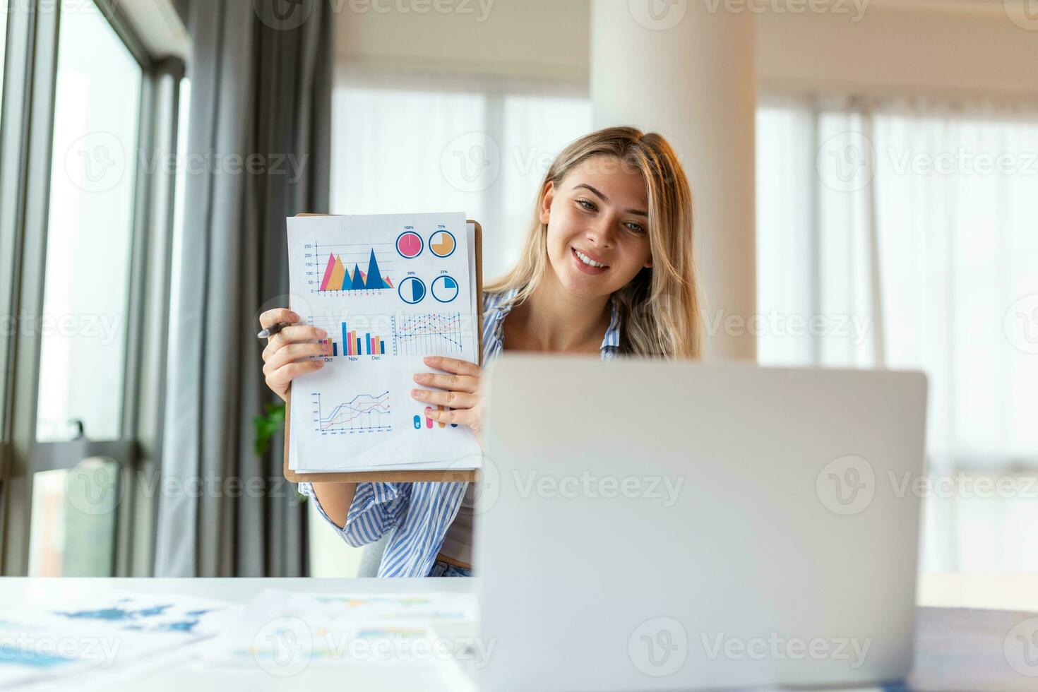 Focused business woman presenting charts and graphs on video call online. Young business woman having conference call with client on laptop. Young woman explaining how business work photo