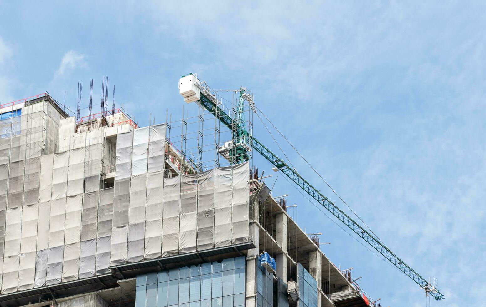 Tower construction crane in rooftop building construction site with blue sky background photo