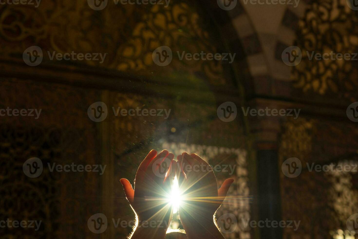 Islamic background photo. Muslim man praying with hands and direct sunlight photo