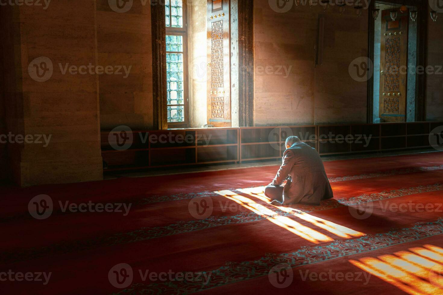 Islamic photo. Muslim man praying in the mosque. Sunlight rays and haze photo