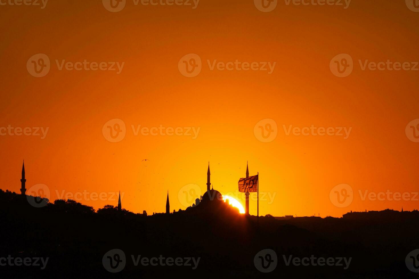 Istanbul silhouette at sunset. Mosque and minarets with flag. photo