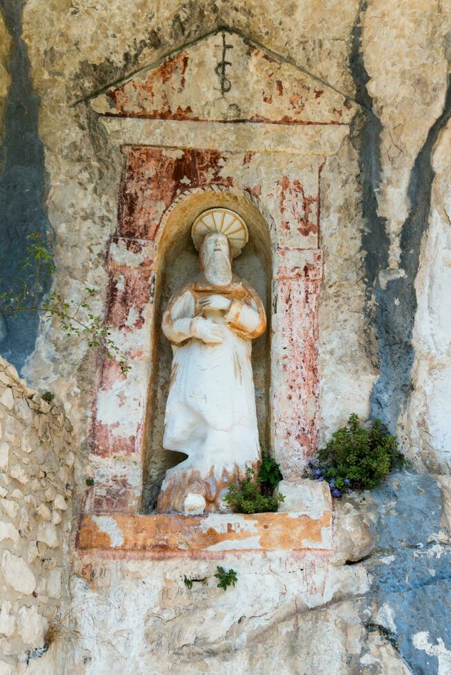 L'Aquila, Italy-august 12, 2021-ruins of the Hermitage of the Holy Spirit an ancient church dug into a cliff with a well-preserved fresco, altar and hermit's cells. photo