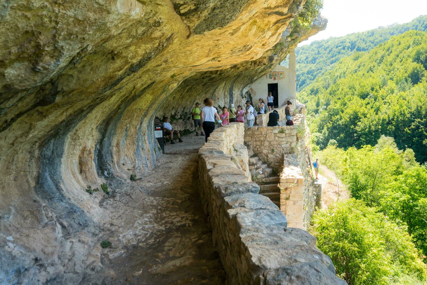 L'Aquila, Italy-august 12, 2021-People visit the Hermitage of San Bartolomeo an ancient church dug into a cliff with a well-preserved fresco, altar and hermit's cells. photo