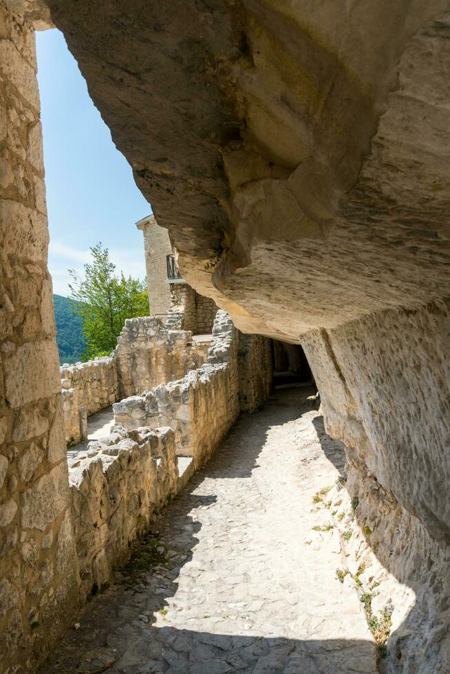 L'Aquila, Italy-august 12, 2021-ruins of the Hermitage of the Holy Spirit an ancient church dug into a cliff with a well-preserved fresco, altar and hermit's cells. photo