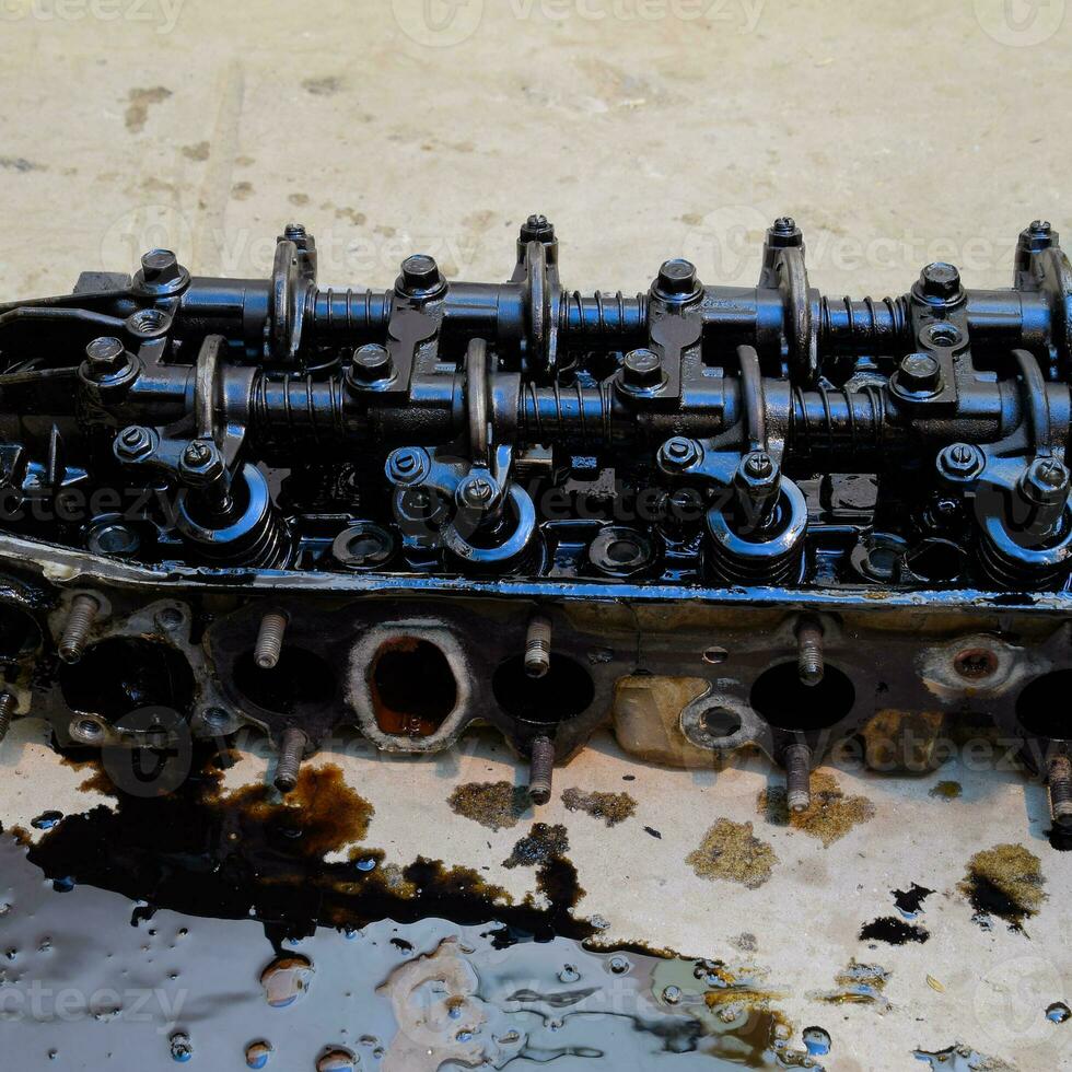The head of the block of cylinders. The head of the block of cylinders removed from the engine for repair. Parts in engine oil. Car engine repair in the service photo