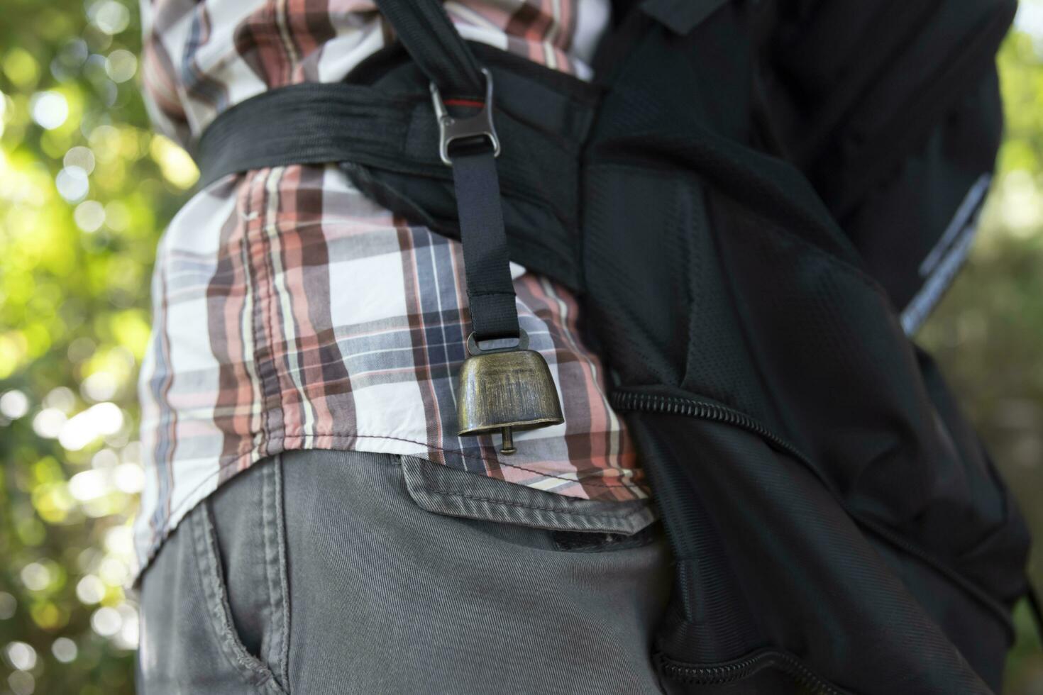 A person who wear a backpack with bear bell at the green forest in Autumn photo