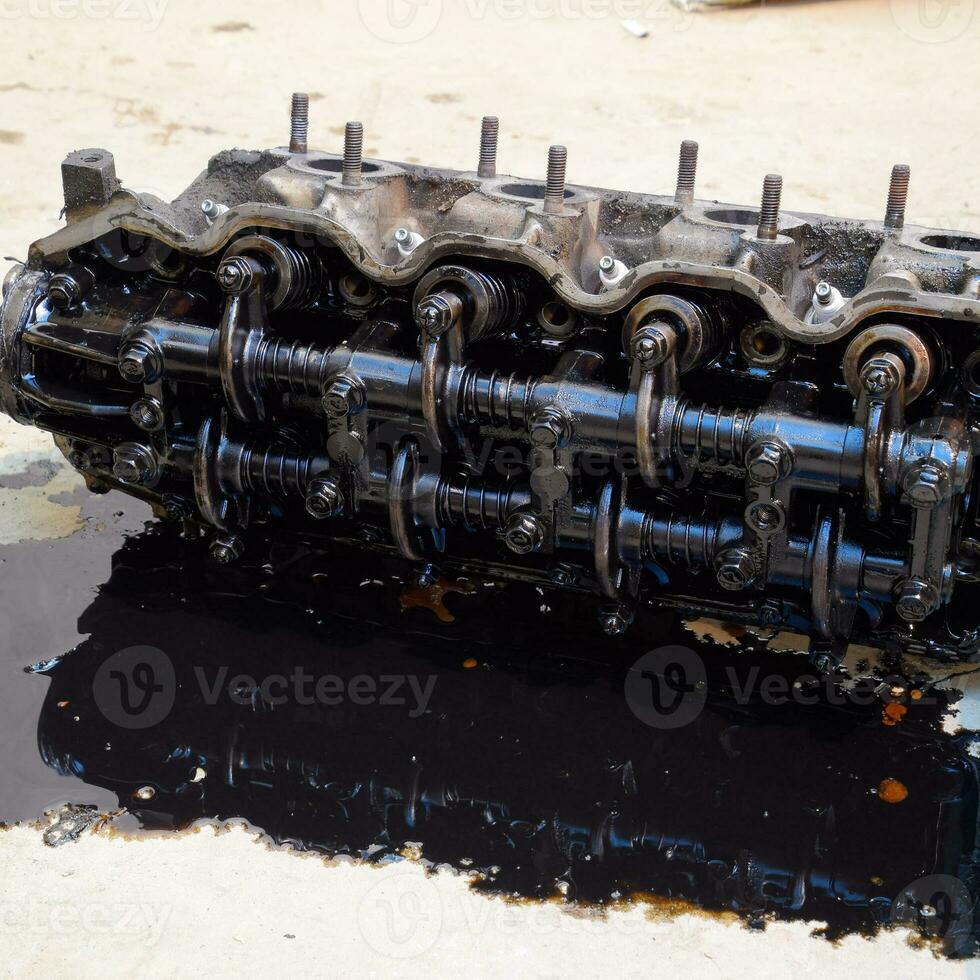 The head of the block of cylinders. The head of the block of cylinders removed from the engine for repair. Parts in engine oil. Car engine repair in the service photo