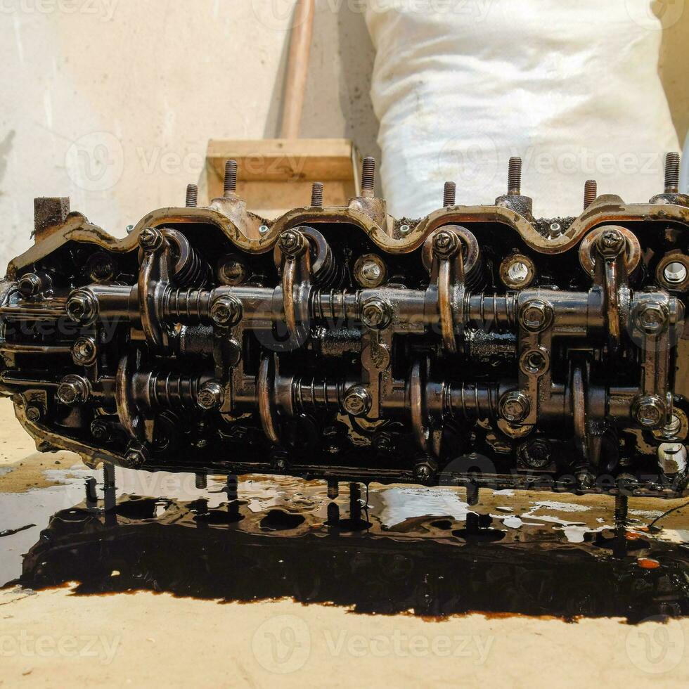 The head of the block of cylinders. The head of the block of cylinders removed from the engine for repair. Parts in engine oil. Car engine repair in the service photo