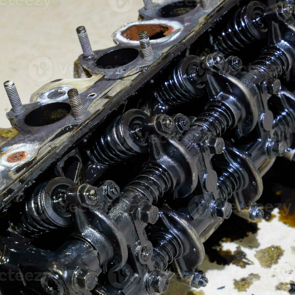 The head of the block of cylinders. The head of the block of cylinders removed from the engine for repair. Parts in engine oil. Car engine repair in the service photo