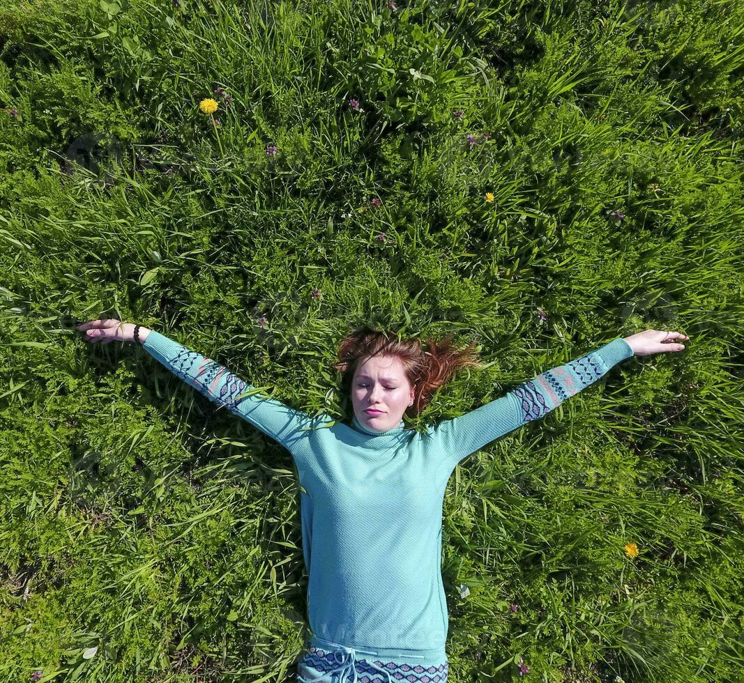 The girl lies in a turquoise dress on the lawn. beautiful girl lying down of grass photo