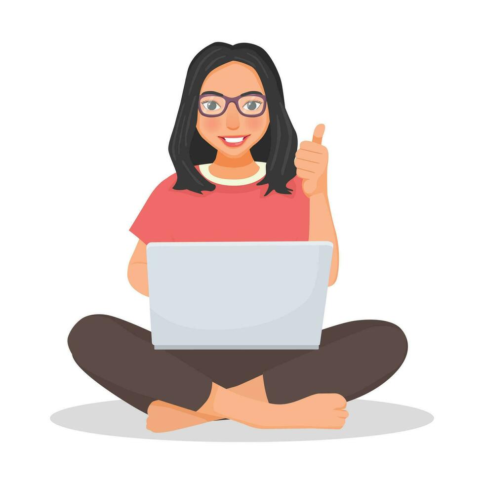 Young woman with glasses using laptop computer while sitting on a floor showing thumb up vector