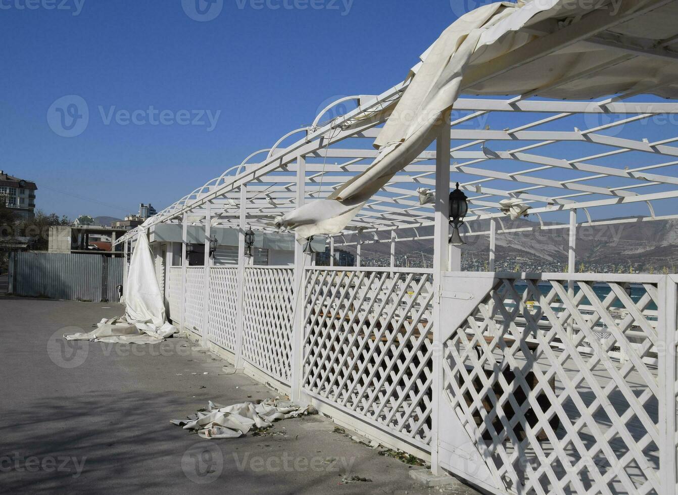 Consequences of the hurricane, torn awning from the gazebo. Garbage and aulitsa on the embankment photo