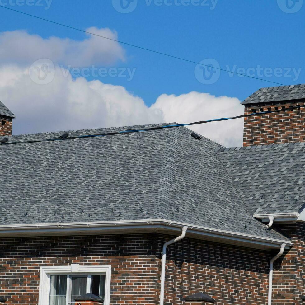 Asphalt shingle. Decorative bitumen shingles on the roof of a brick house. photo