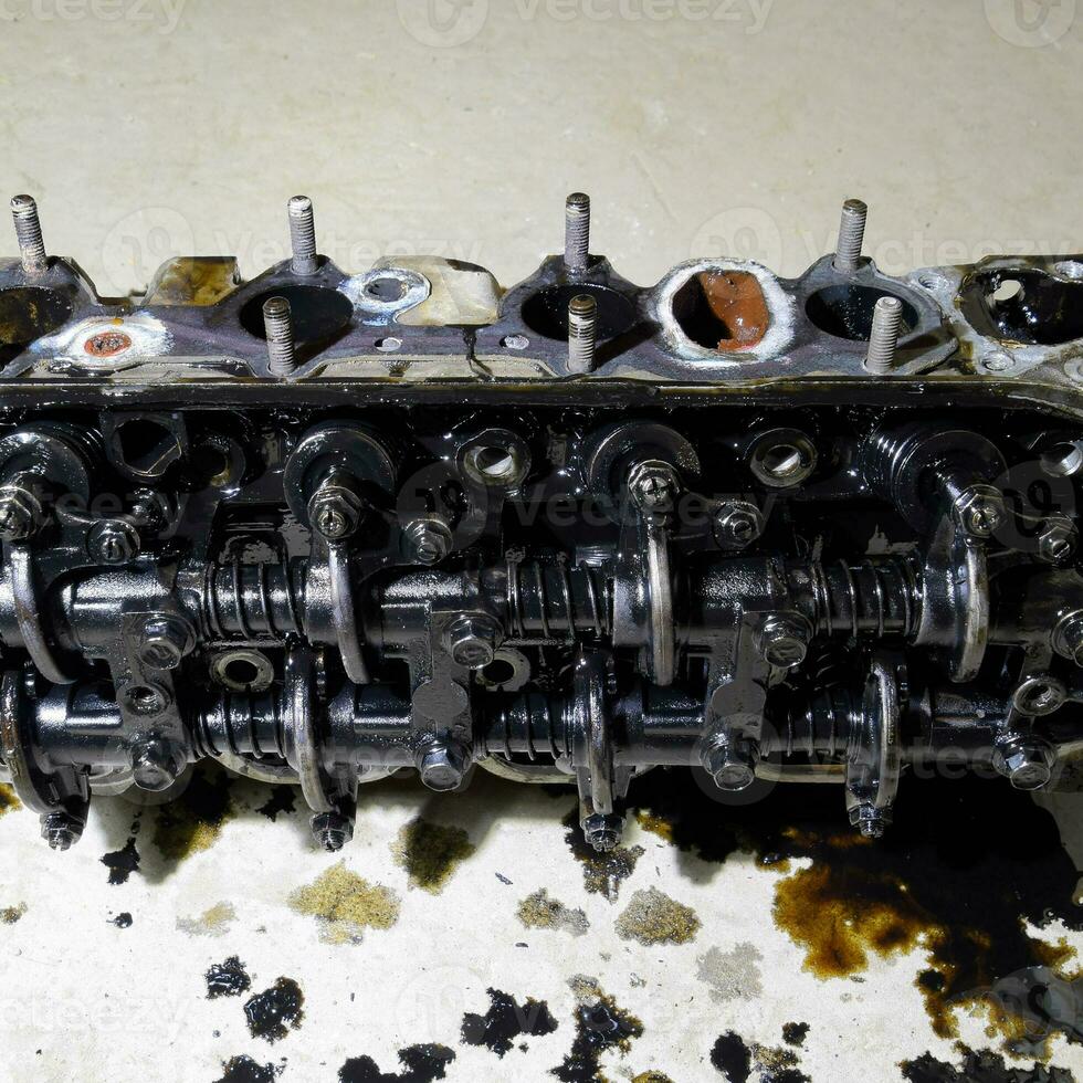 The head of the block of cylinders. The head of the block of cylinders removed from the engine for repair. Parts in engine oil. Car engine repair in the service photo