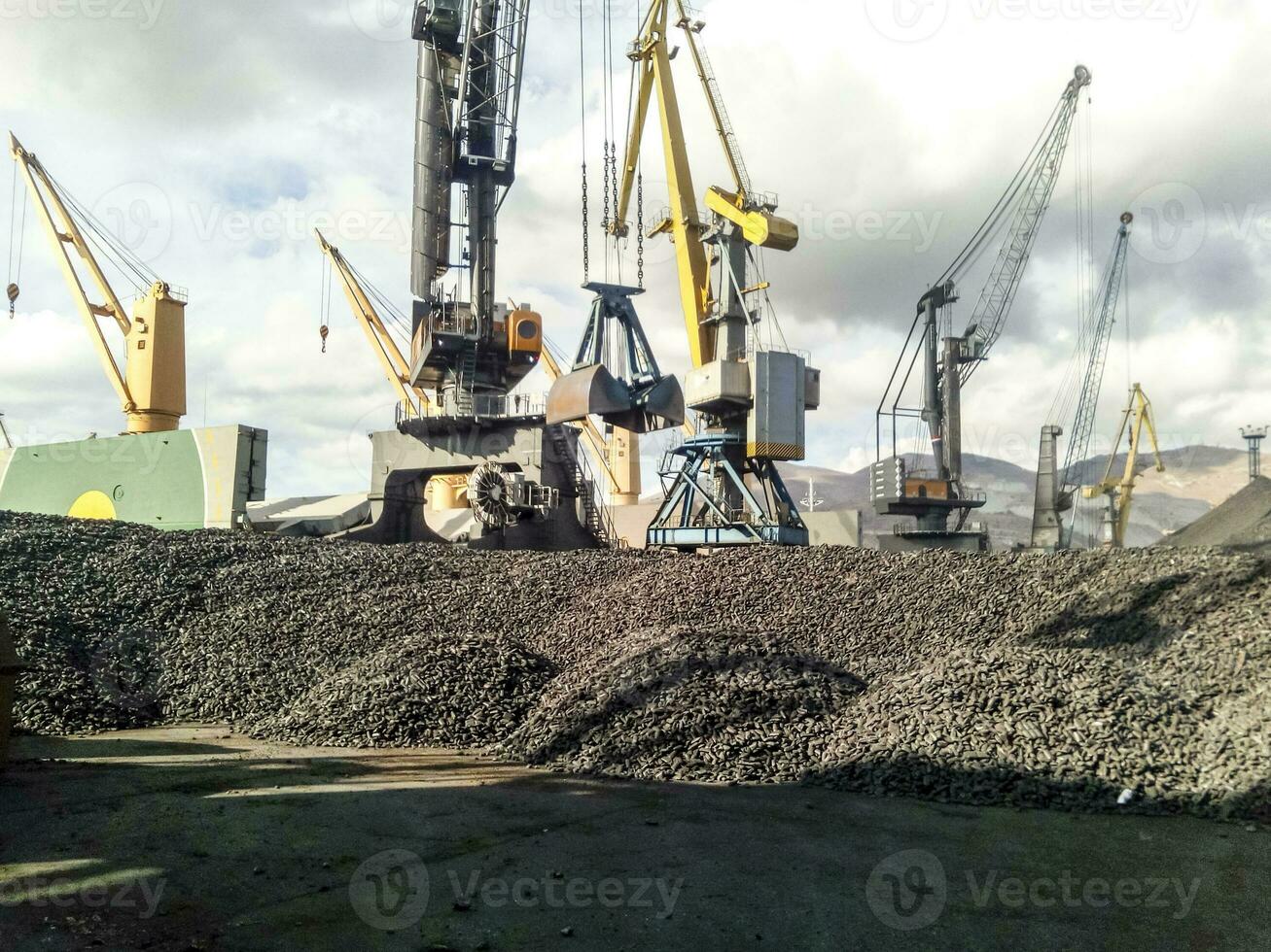 Heap of coal anthracite in the port. Port cranes for coal loading photo