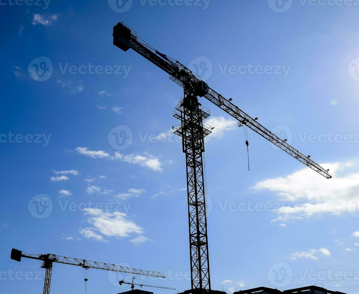 Tower building crane against the blue sky and sun. Construction of new buildings with a crane. Tower crane photo