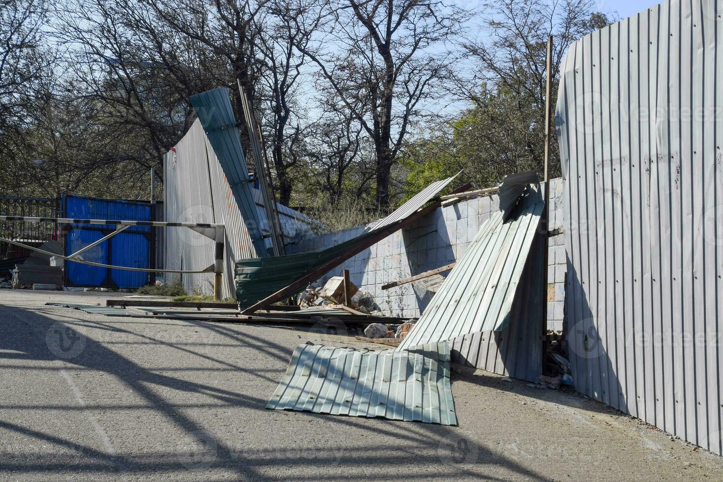 Ruined fence made of corrugated metal. Consequences of the hurricane photo