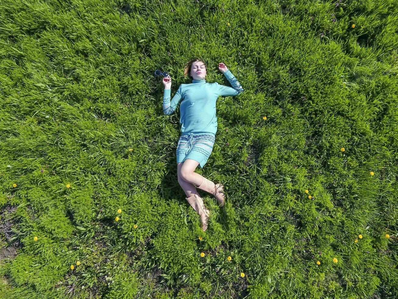 The girl lies in a turquoise dress on the lawn. beautiful girl lying down of grass photo