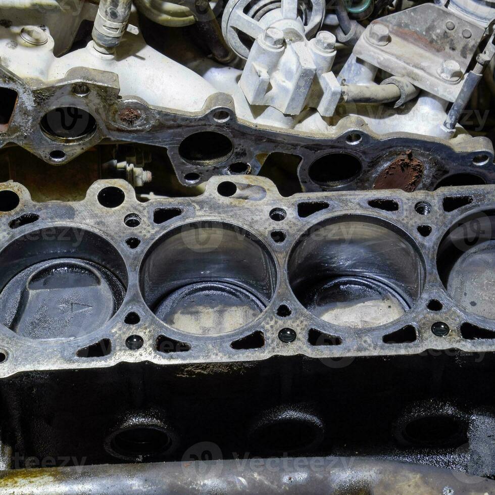 The cylinder block of the four-cylinder engine. Disassembled motor vehicle for repair. Parts in engine oil. Car engine repair in the service photo