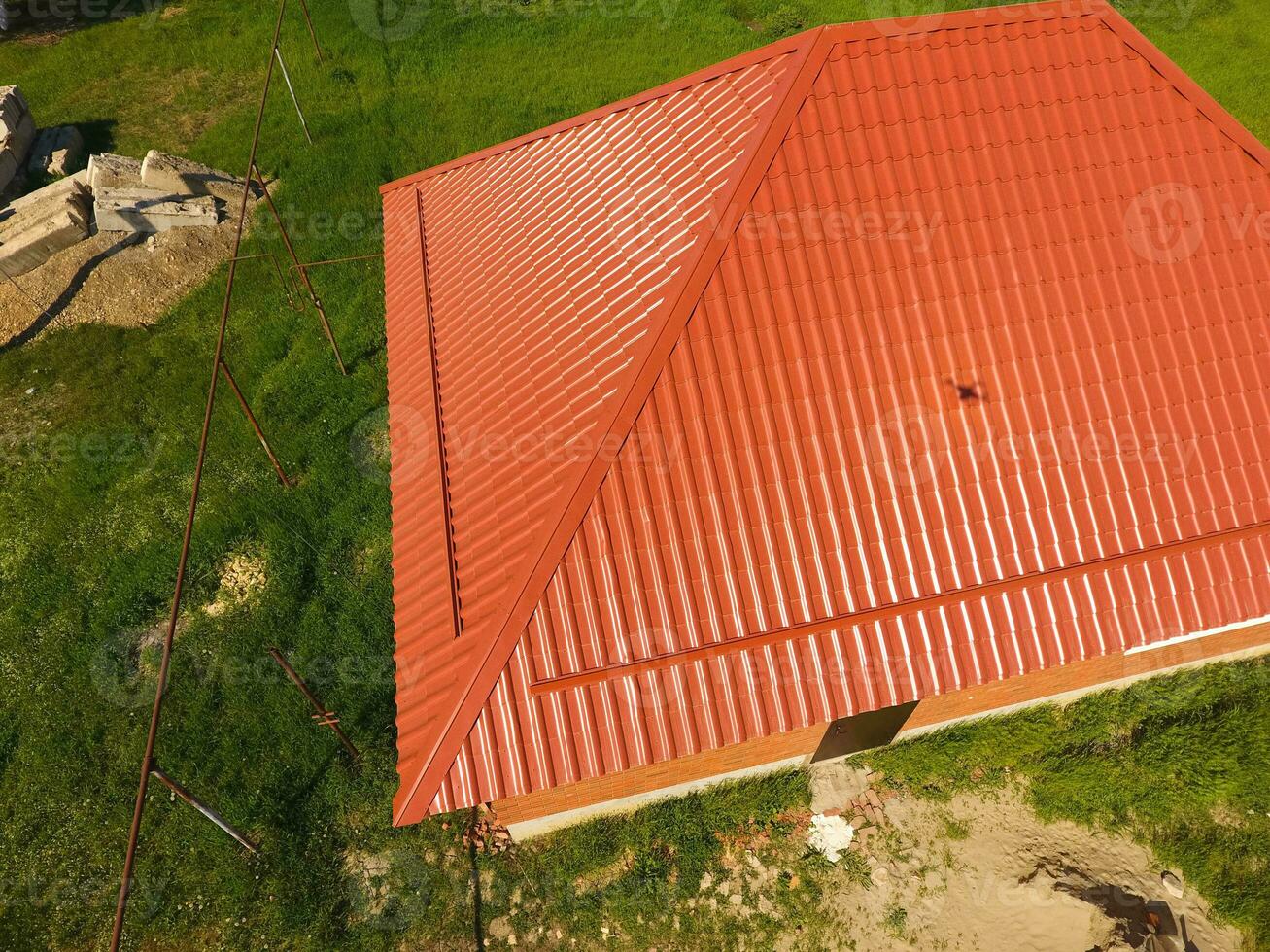House with an orange roof made of metal, top view. Metallic profile painted corrugated on the roof. photo