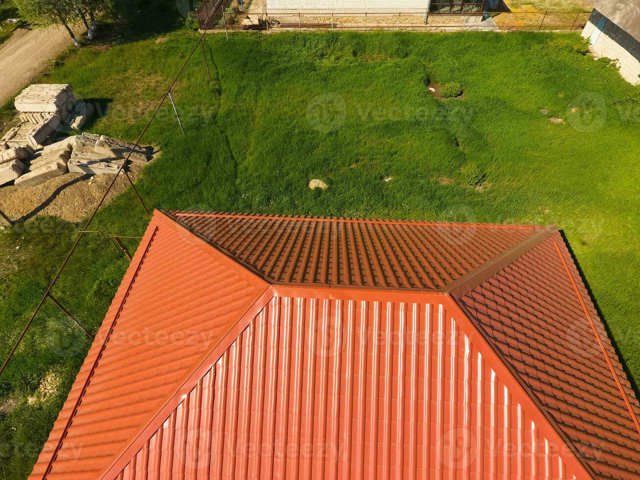 House with an orange roof made of metal, top view. Metallic profile painted corrugated on the roof. photo