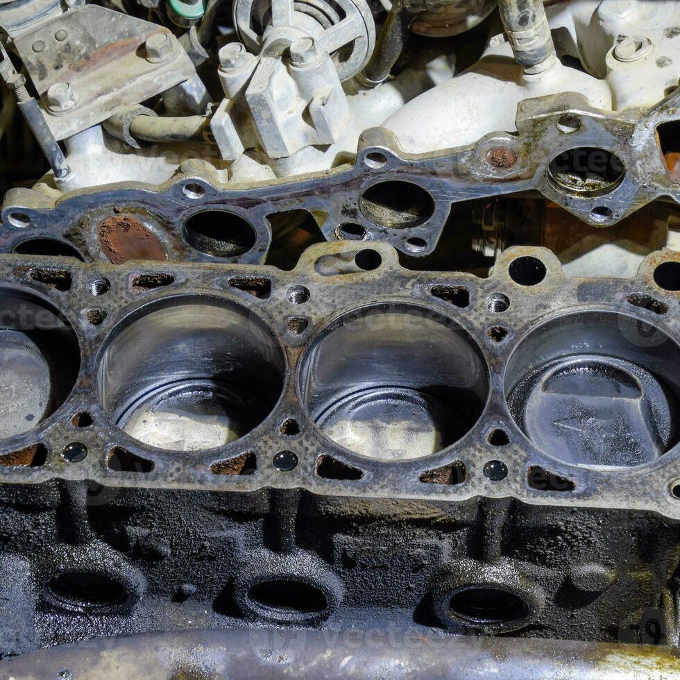 The cylinder block of the four-cylinder engine. Disassembled motor vehicle for repair. Parts in engine oil. Car engine repair in the service photo