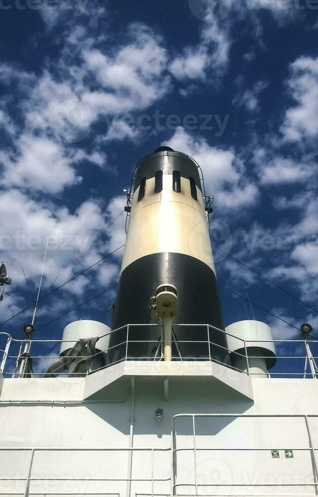 Pipe on the ship. White ship with a black chimney against the sky with clouds photo