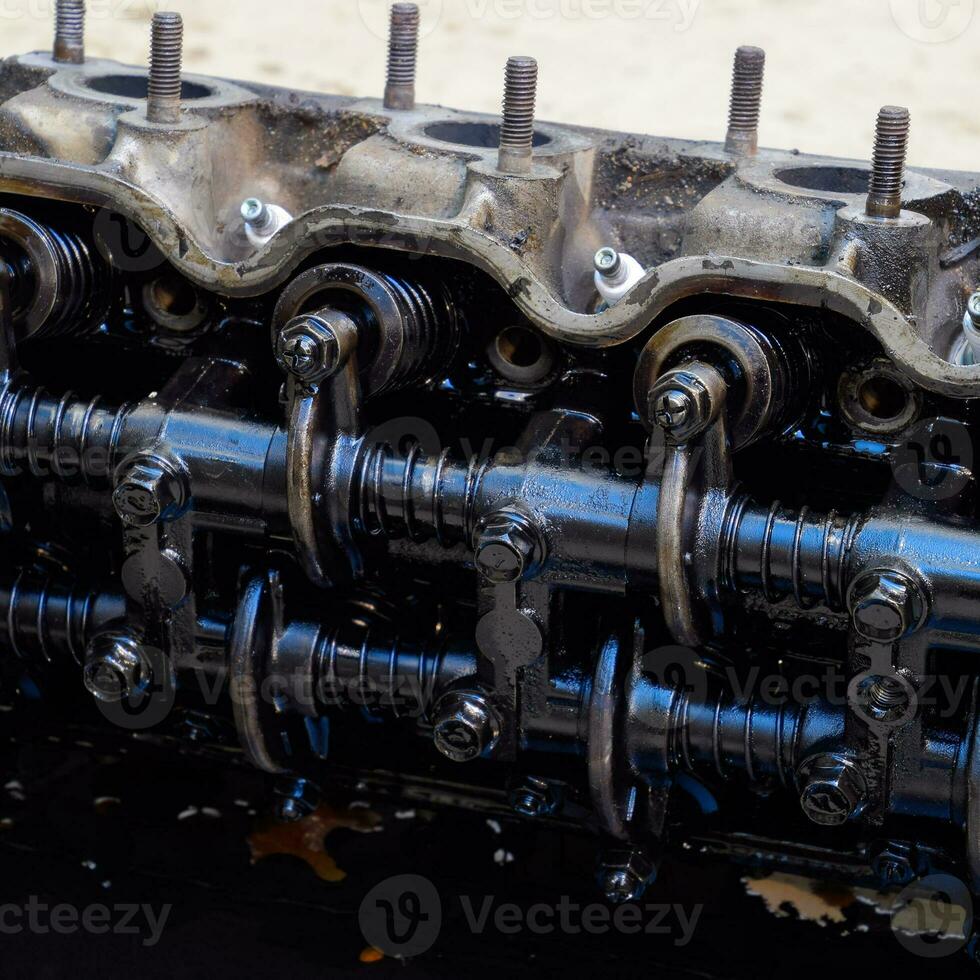 The head of the block of cylinders. The head of the block of cylinders removed from the engine for repair. Parts in engine oil. Car engine repair in the service photo