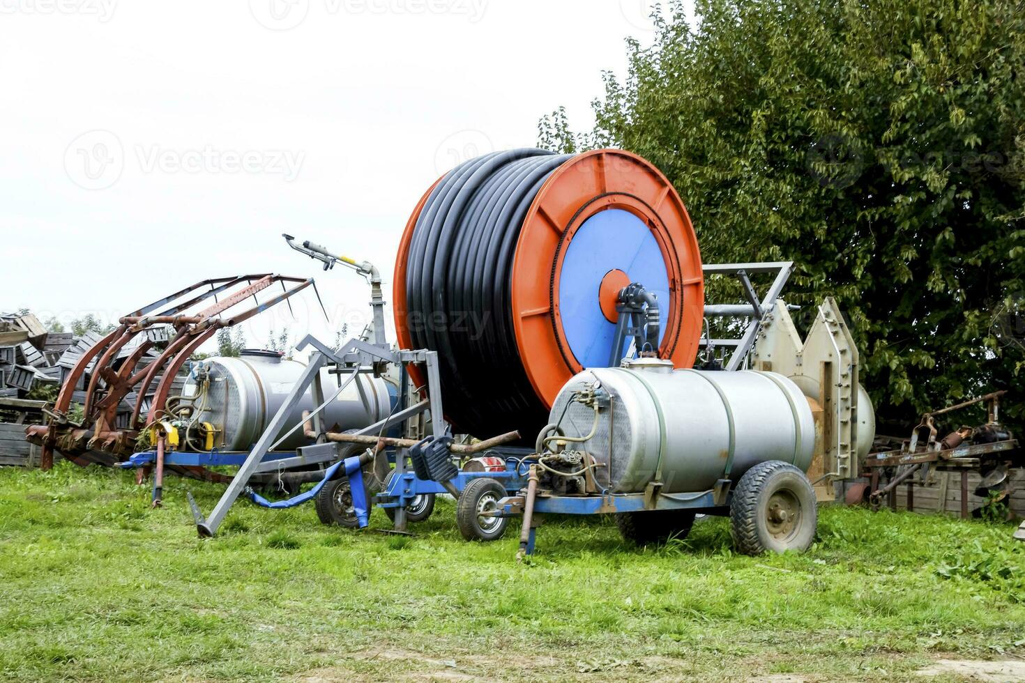 Trailers with fertilizer tanks and a drum with a watering hose. photo