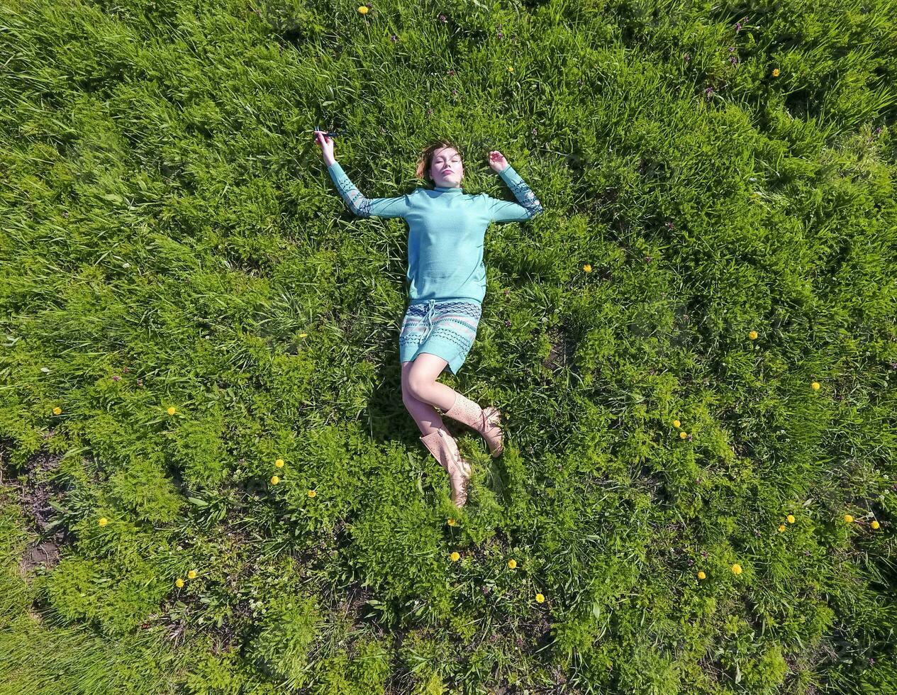 The girl lies in a turquoise dress on the lawn. beautiful girl lying down of grass photo