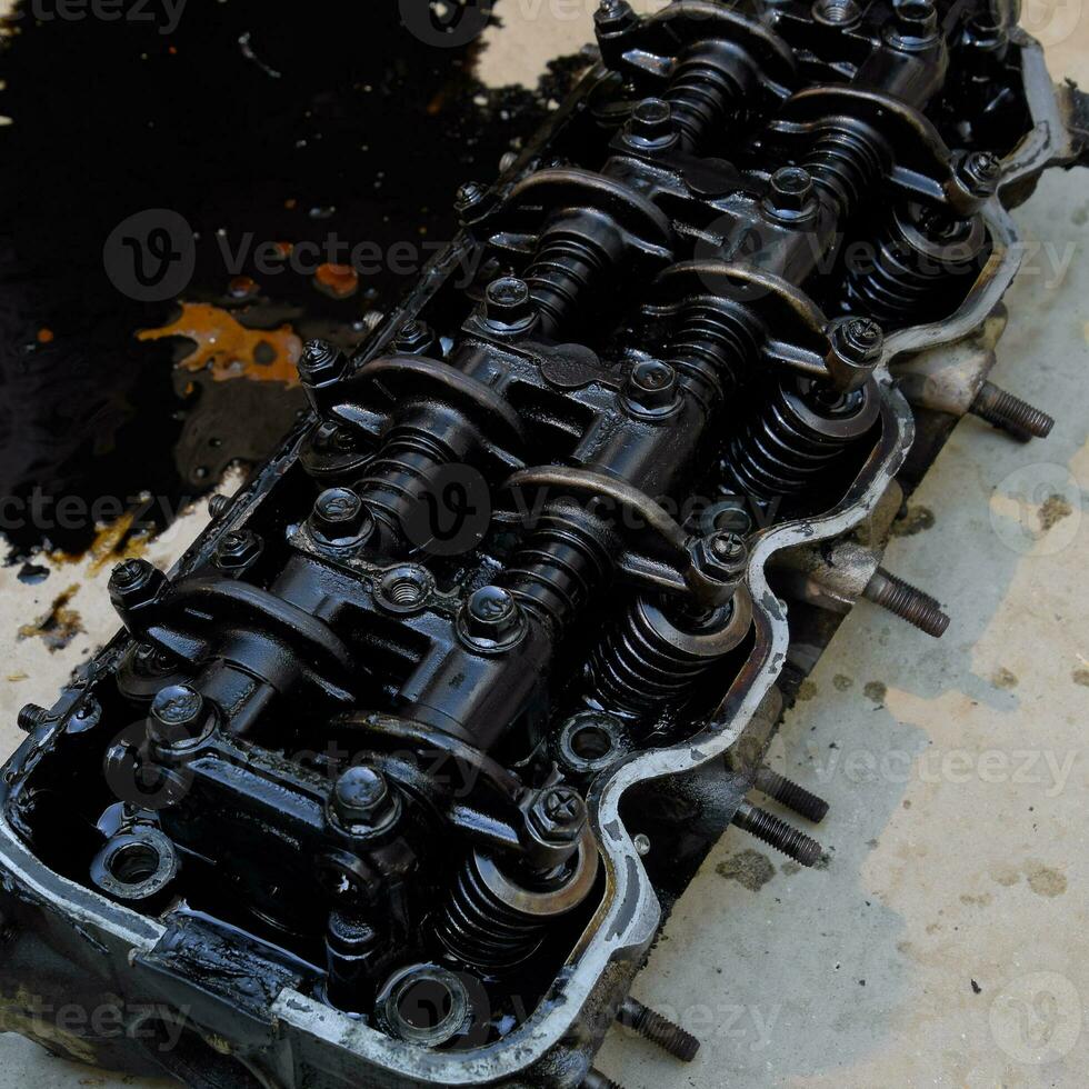 The head of the block of cylinders. The head of the block of cylinders removed from the engine for repair. Parts in engine oil. Car engine repair in the service photo