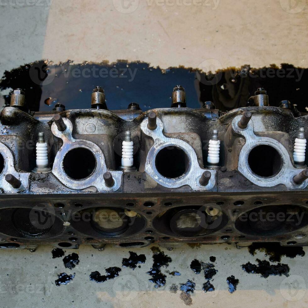 The head of the block of cylinders. The head of the block of cylinders removed from the engine for repair. Parts in engine oil. Car engine repair in the service photo