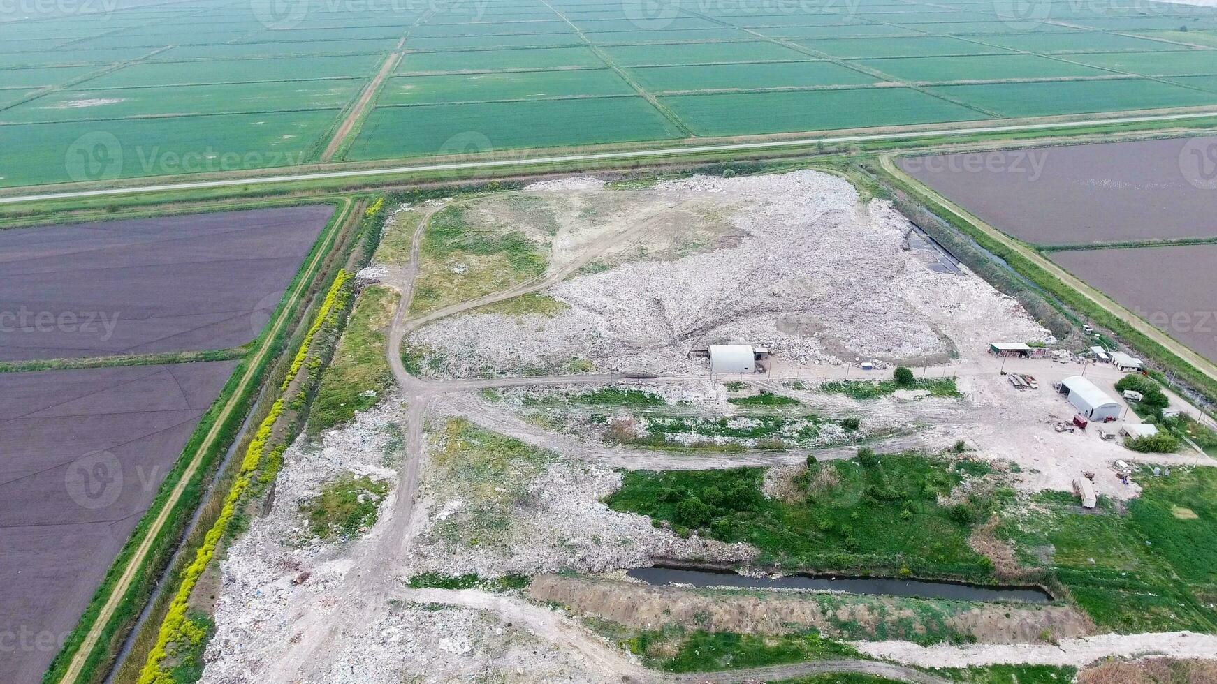 garbage dump with heaps of garbage and treatment facilities. Landfill of garbage outside the village photo