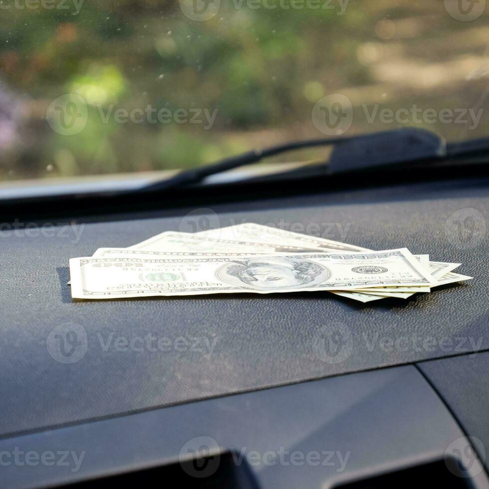 Dollars on a car dashboard under the windshield. American Money photo