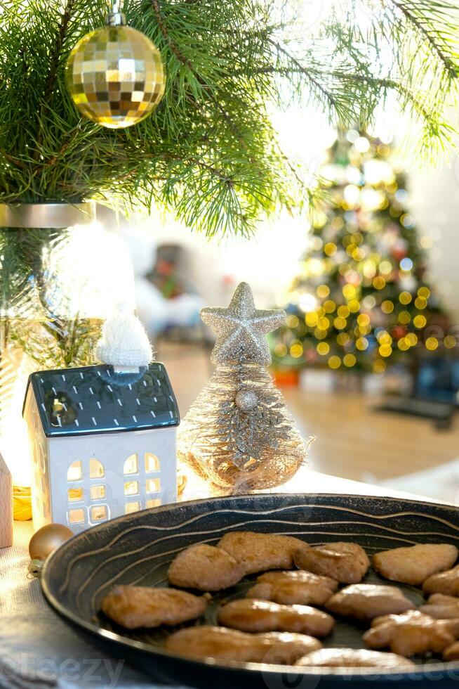 Festive Christmas decor in table, homemade cakes for breakfast, bakery cookies. Cozy home, christmas tree with fairy lights garlands. New Year, christmas mood photo