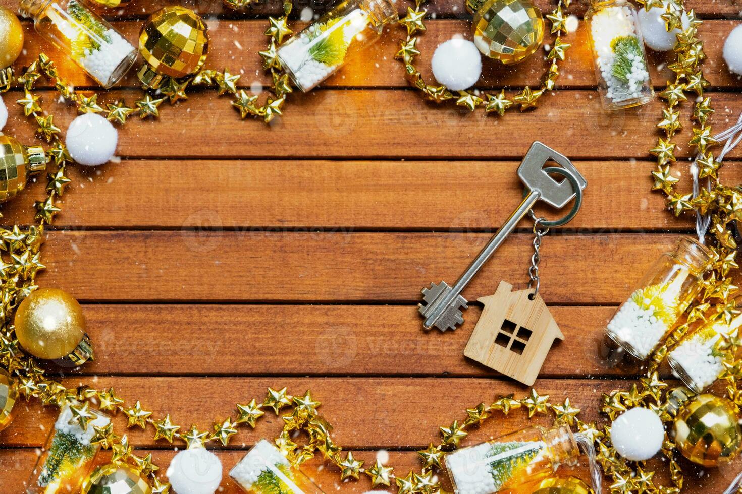 Key to house with a keychain tiny home on wooden background with Christmas decor layout. Gift for New Year, Christmas. Building, project, moving to new house, mortgage, rent and purchase real estate photo