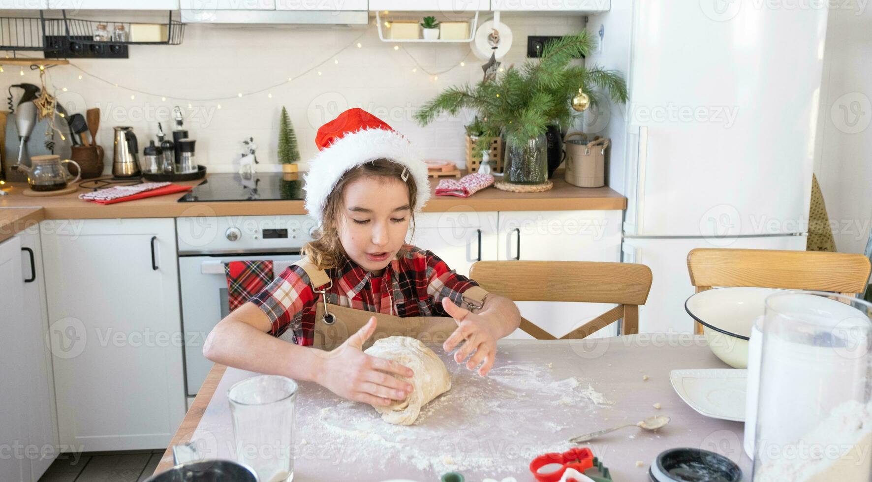 Daughter learning to cook helps in the white kitchen knead the dough in the bowl for gingerbread and cookies for Christmas and new year. Put the ingredients photo