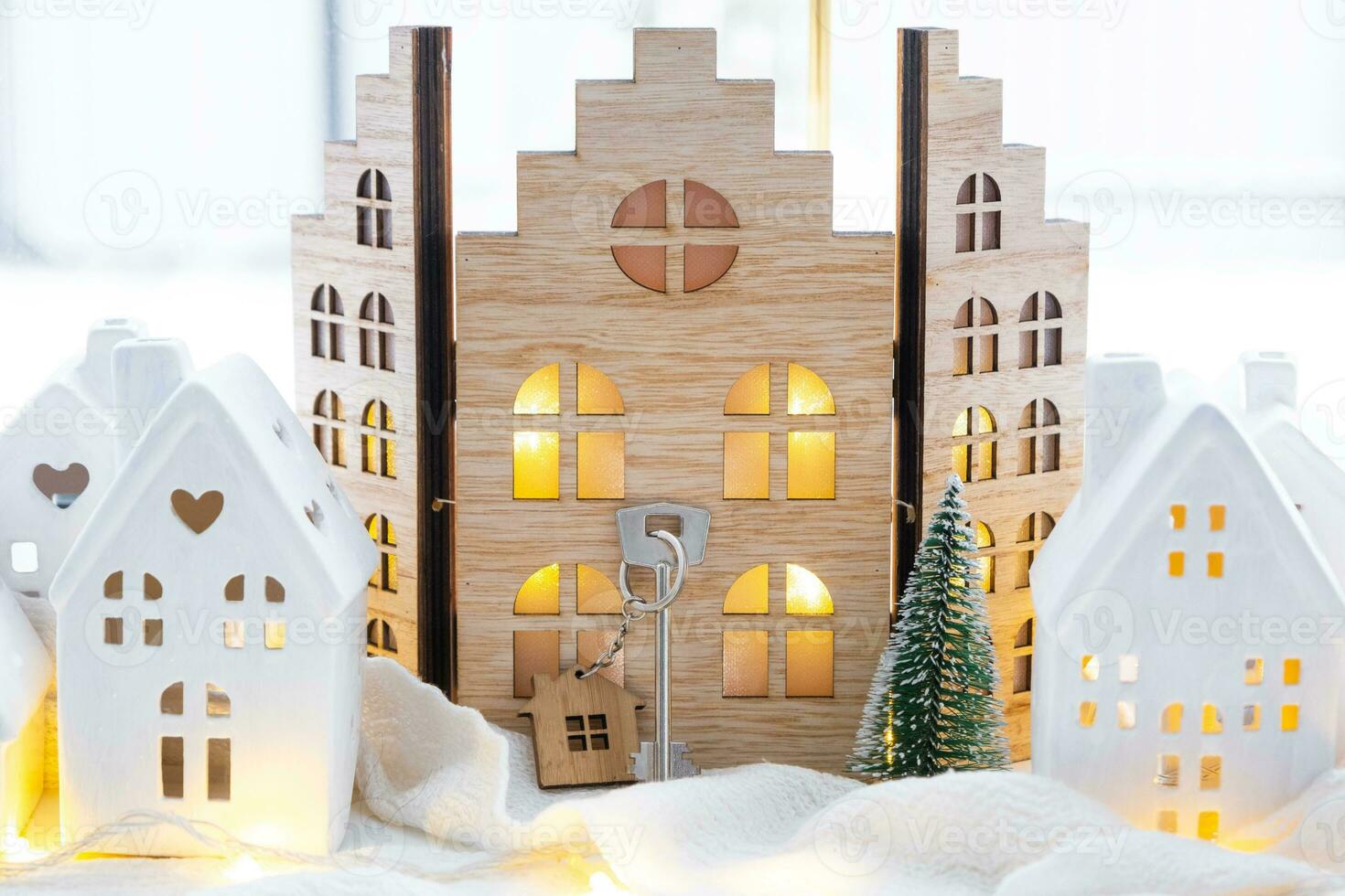 Key and tiny house of a small size on cozy home with Christmas decor on window sill. Gift for New Year. Insurance, moving to new house, mortgage, rent and purchase real estate photo