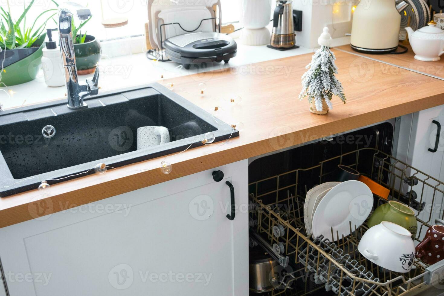 A lot of dirty dishes in the dishwasher in the festive kitchen. Helping the hostess, economy and ecology. Cleaning in the kitchen for the holidays of Christmas and New Year, after the feast and guests photo
