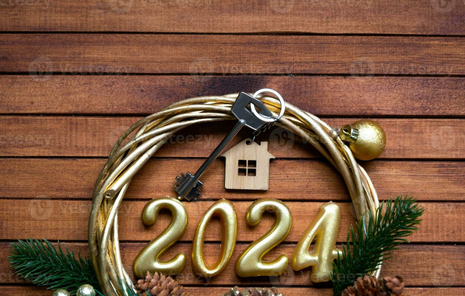 House key with keychain cottage on festive brown wooden background with stars, lights of garlands. New Year 2024 wooden letters, greeting card. Purchase, construction, relocation, mortgage, insurance photo