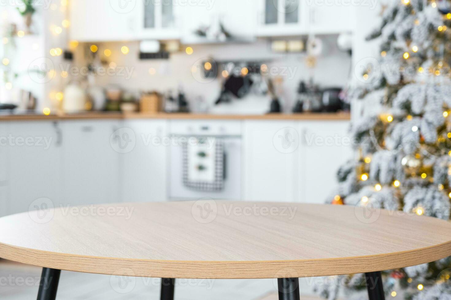 Round empty table to demonstrate the product with space for text in white kitchen, modern interior with a Christmas tree and fairy lights. New Year, Christmas mood, cozy home. photo