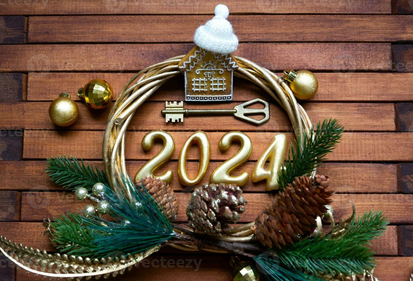 House key with keychain cottage on festive brown wooden background with stars, lights of garlands. New Year 2024 wooden letters, greeting card. Purchase, construction, relocation, mortgage, insurance photo