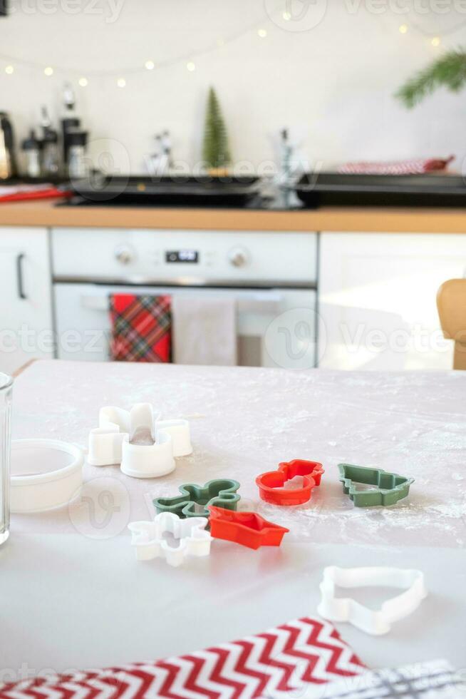 diseño de Galleta cortadores de cerca cortar fuera galletas desde el masa con moldes en un Navidad tema en el formar de un muñeco de nieve, un Navidad árbol, estrellas en el cocina foto