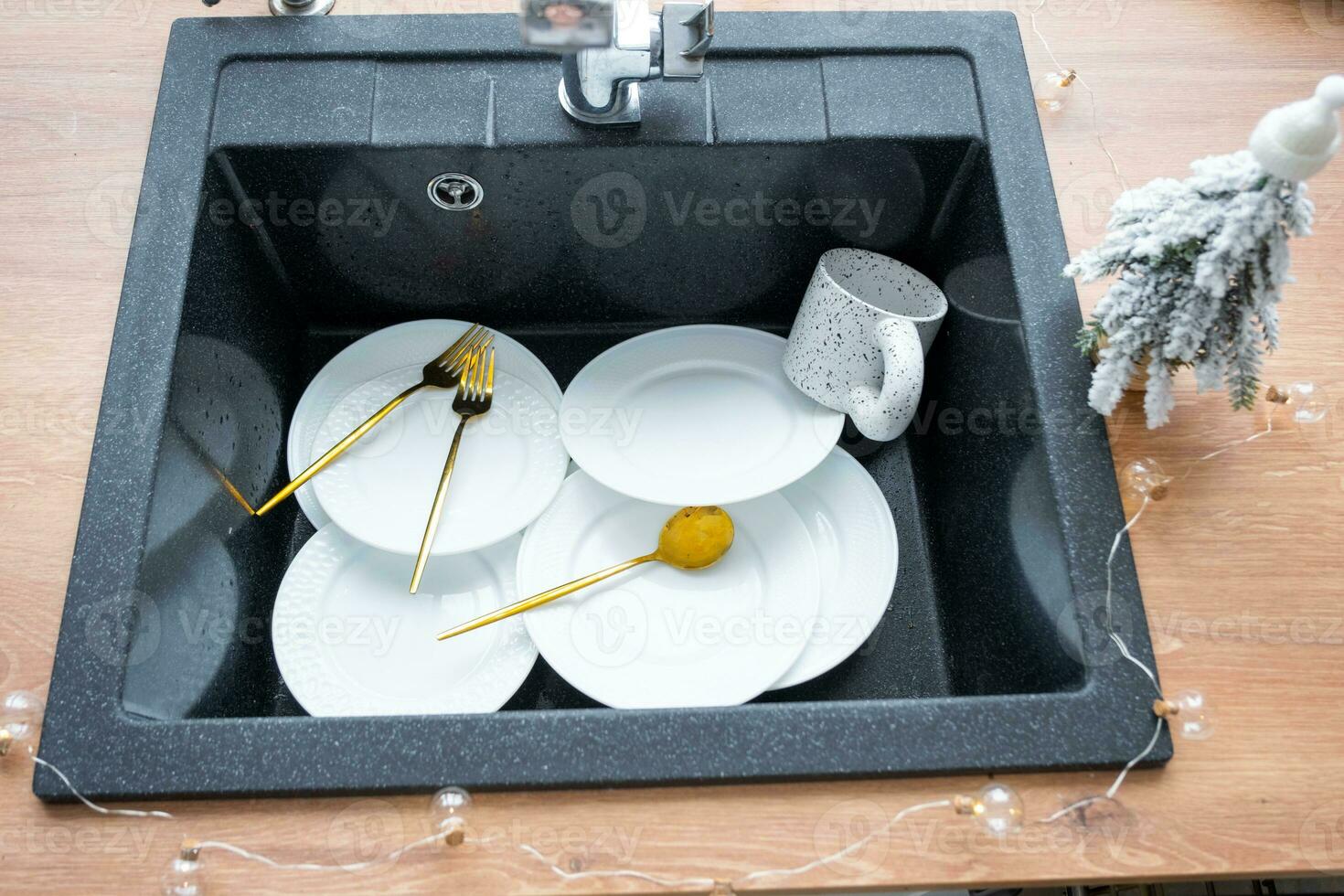 Dirty dishes in the sink in the garlanded kitchen, a holiday after a feast at Christmas. Mess after the guests for the New Year, kitchen cleaning, detergent, cleaning services photo
