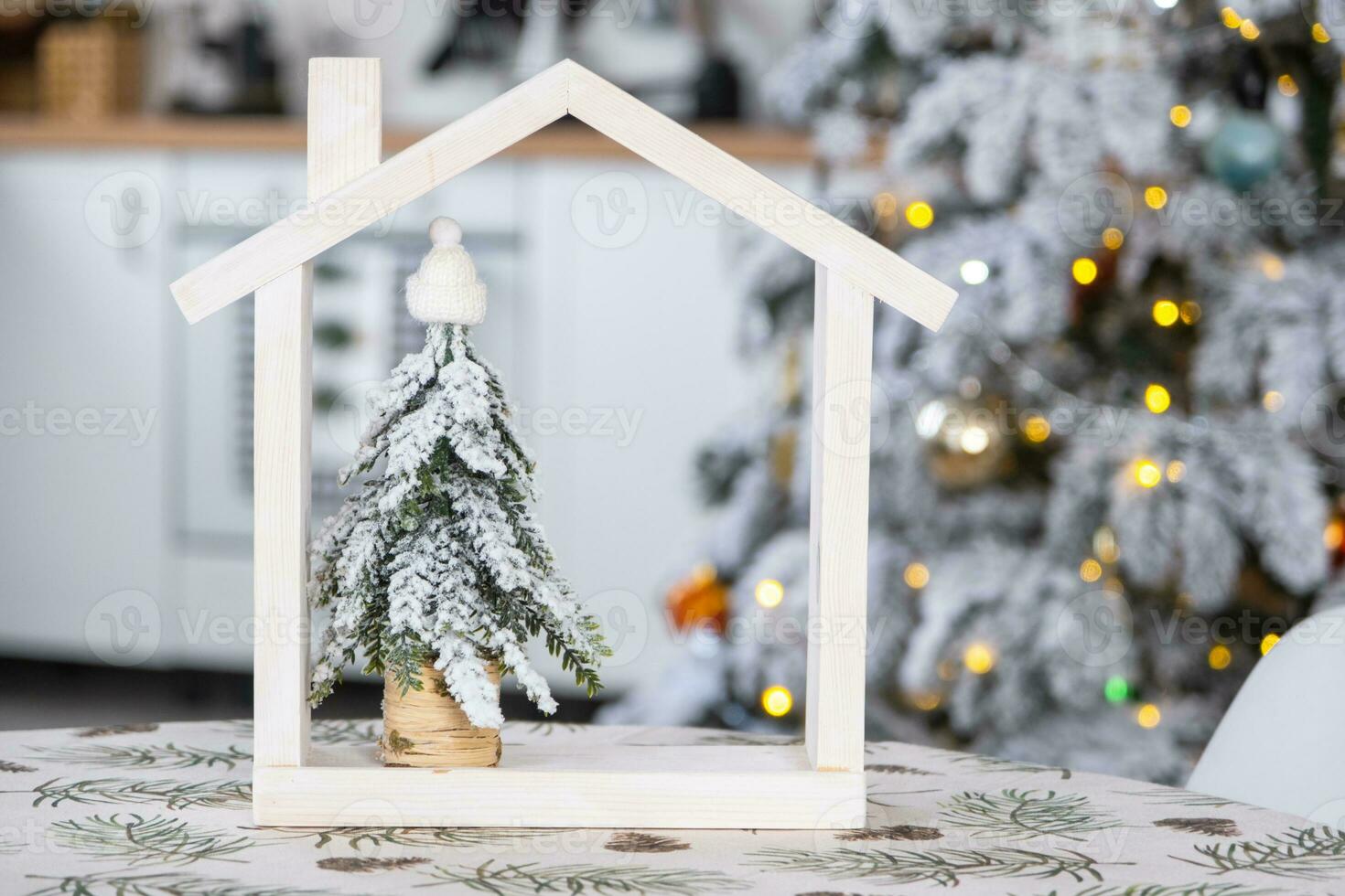 Cozy Christmas decor tiny house of small size on table of festive white modern kitchen. Gift for New Year. Insurance, moving to new house, mortgage, rent and purchase real estate photo