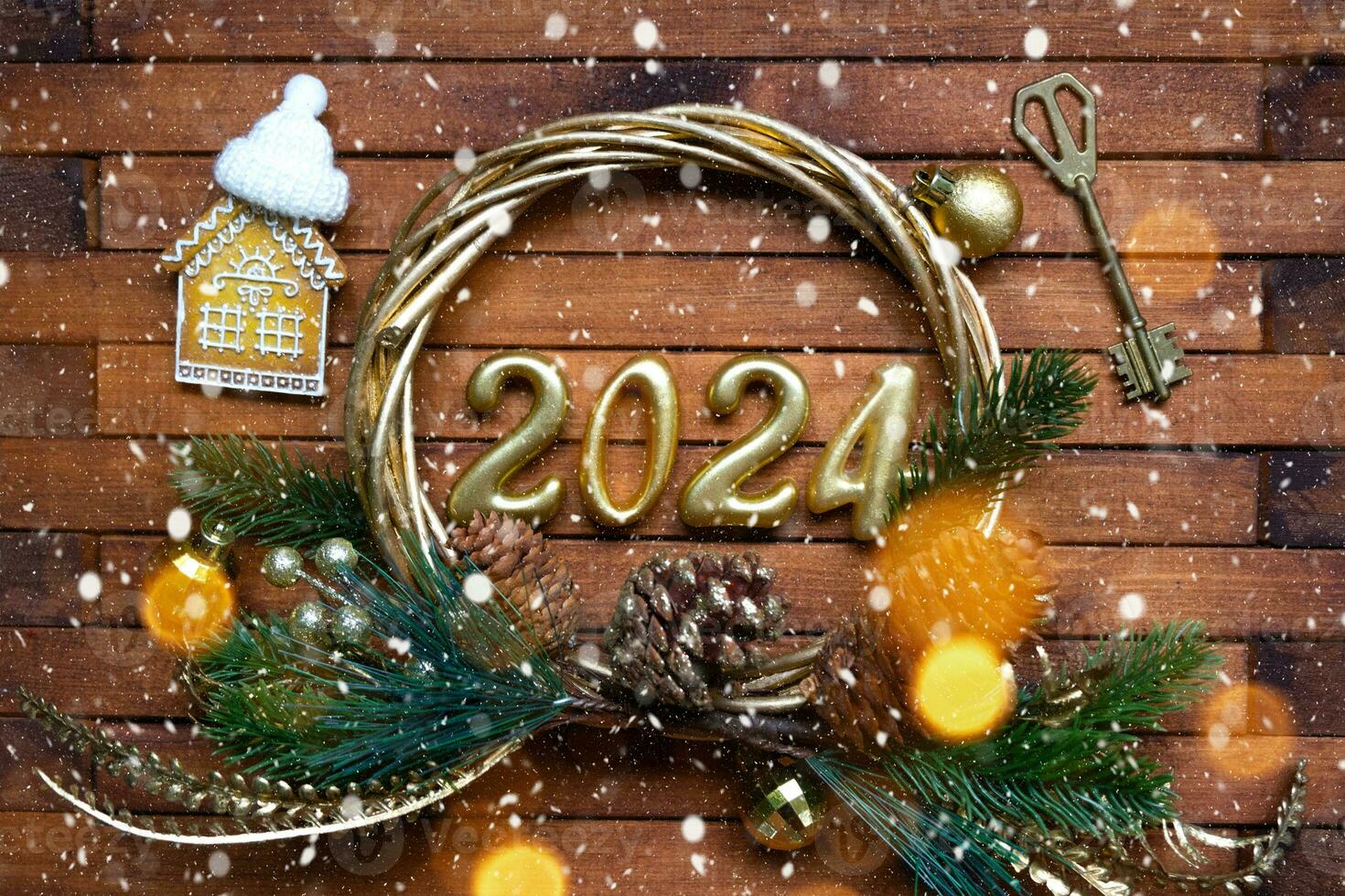 House key with keychain cottage on festive brown wooden background with stars, lights of garlands. New Year 2024 wooden letters, greeting card. Purchase, construction, relocation, mortgage, insurance photo